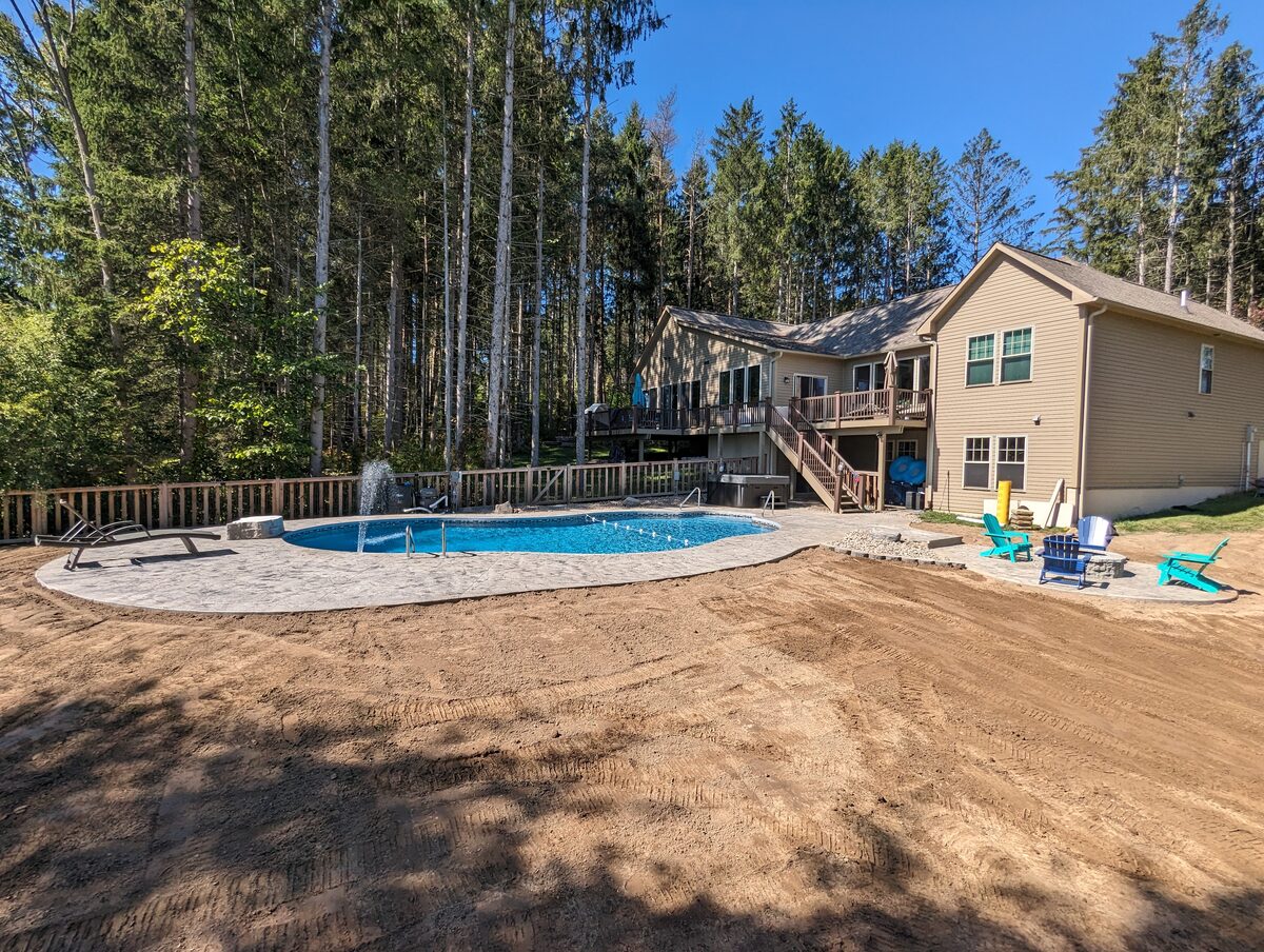 Stamped concrete pool deck and patio behind a Central New York home