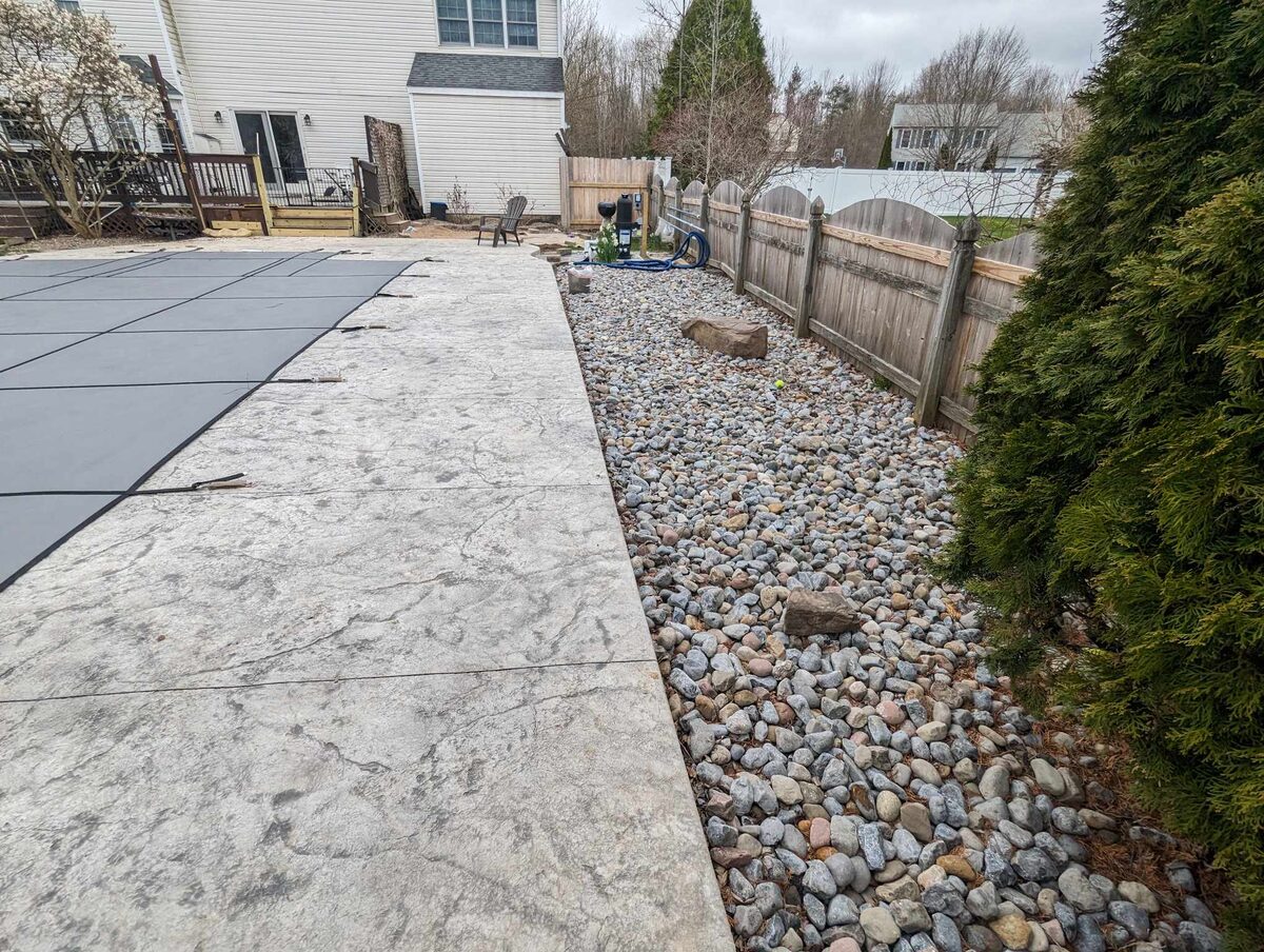 Stamped concrete pool patio with river rock border in Central New York